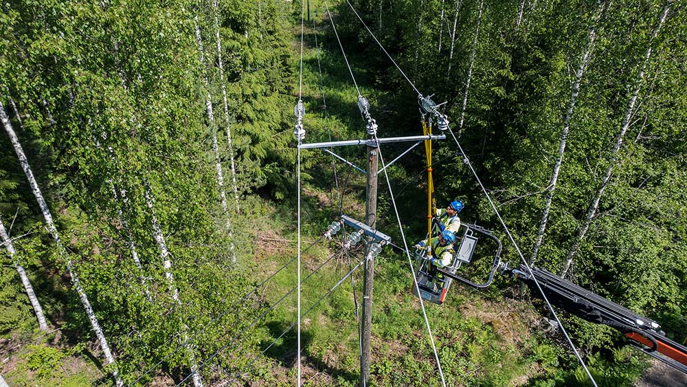 Sähköverkkotyöt käynnissä sähköasentajien toimesta. Sähköverkko menee metsän siimeksessä.