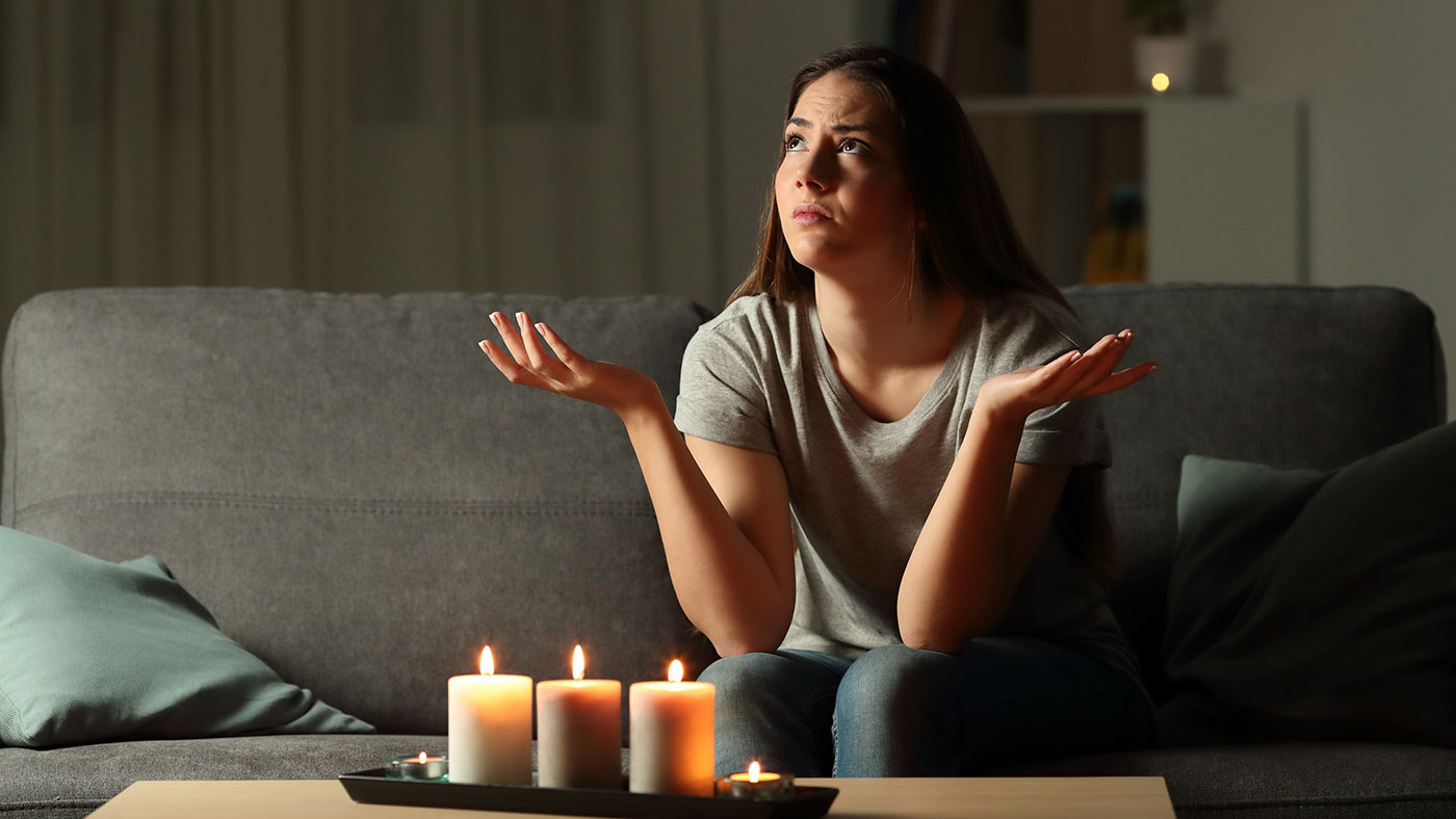 Nainen istuu sohvalla kynttilänvalossa ja on sähkökatko