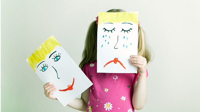 Lapsella kasi paperiarkkia, josta toinen suru ja toinen ilonaama. Lapsi pitää surunaamaarkkia kasvonsa edessä
