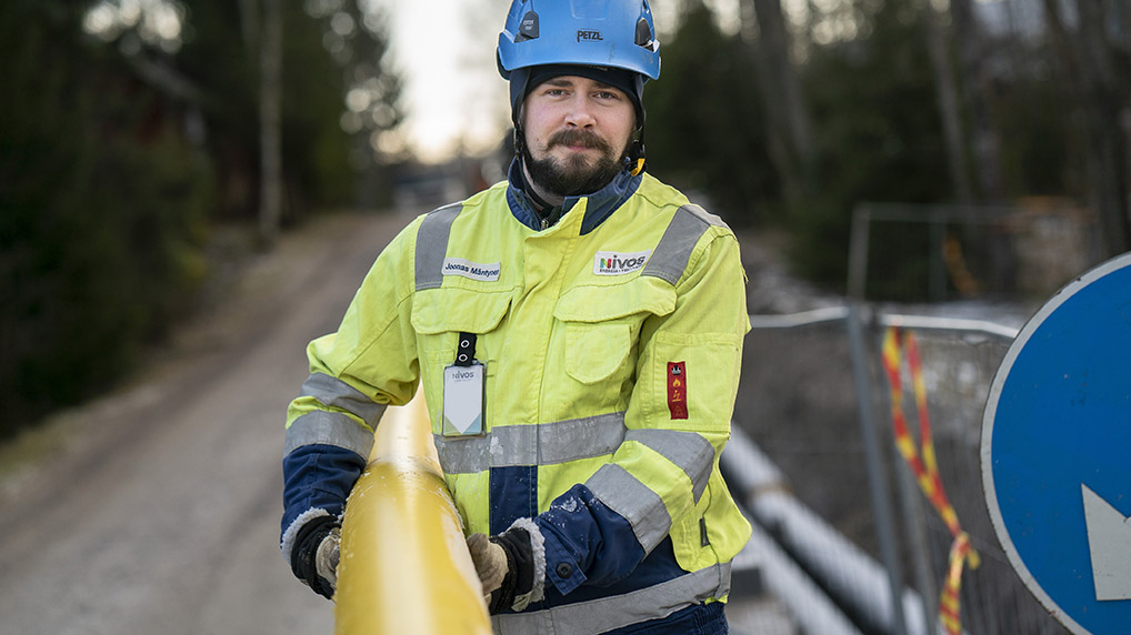 Työntekijämme kaukolämpötyömalla pidellen kaukolämpöputkea. Matkamme kohti fossiilivapaata kaukolämpöä etenee.